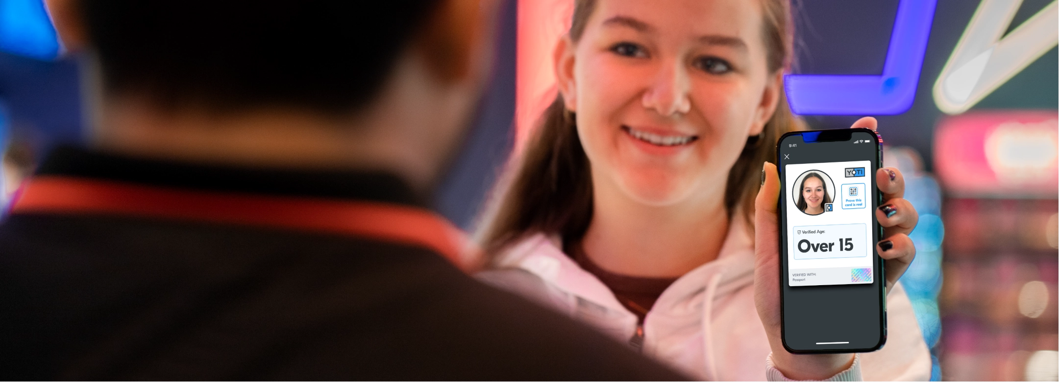 Girl buying cinema tickets and showing her status as an over 15 with her Yoti ID