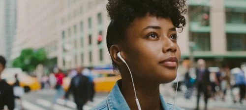 Woman walking through the street listening to her headphones
