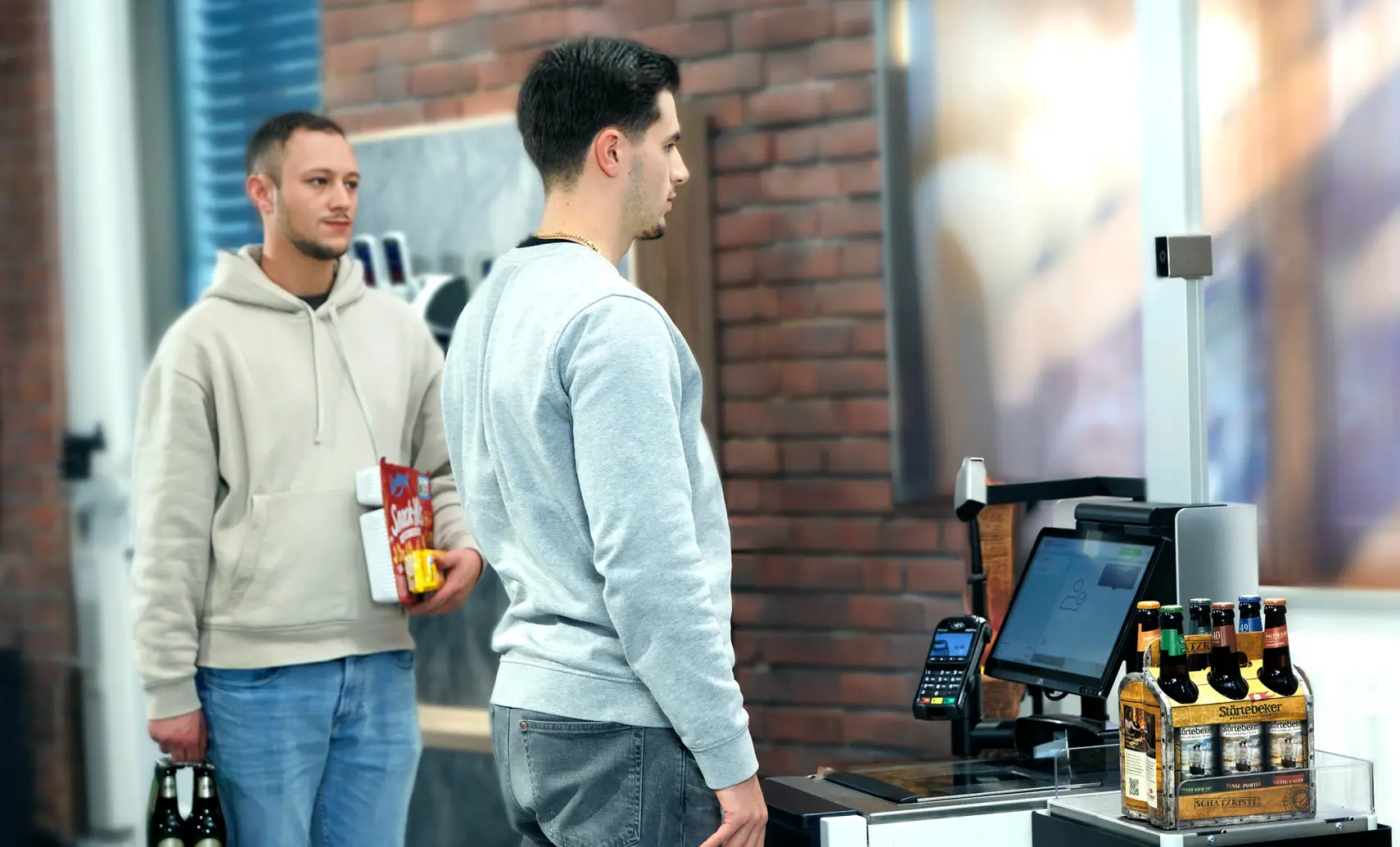 Man using self-checkout terminal to buy a six pack of beers