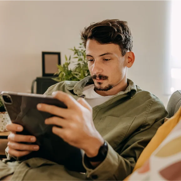 Young man relaxing on sofa using tablet