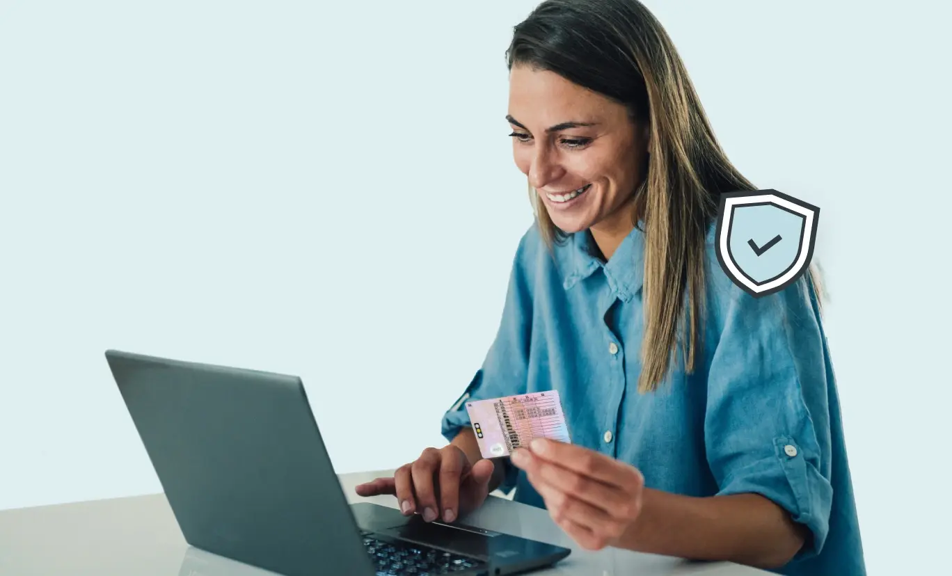 An image of a woman using her driving licence to verify her identity on a laptop.