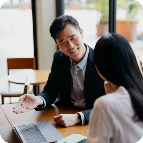 Two people talking in front of a laptop
