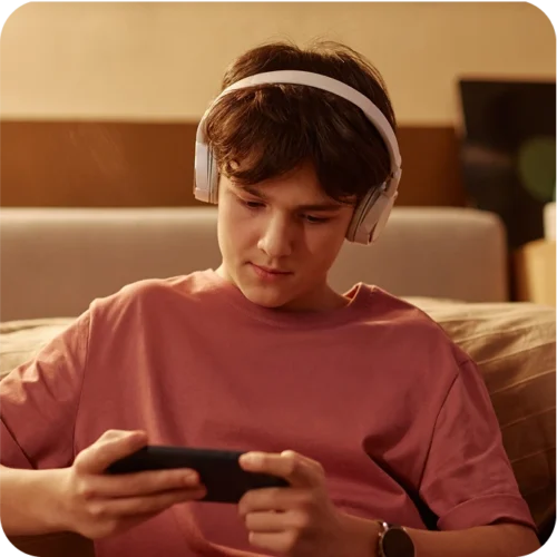 Teenage boy gaming on his phone and wearing over-ear headphones