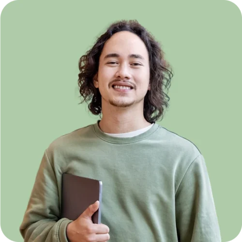 Young man in green sweatshirt holding his laptop under his arm