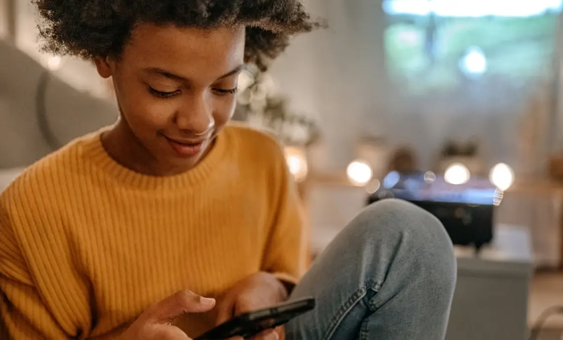 An image of a boy sat at home, using his mobile phone