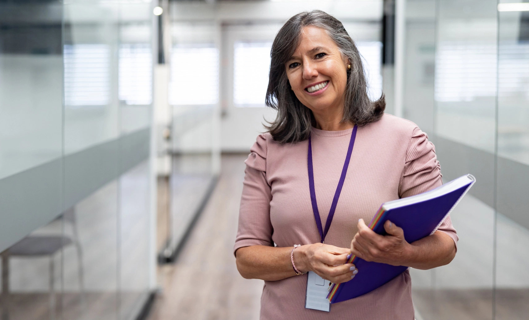 Woman holding folder standing in workplace hallway