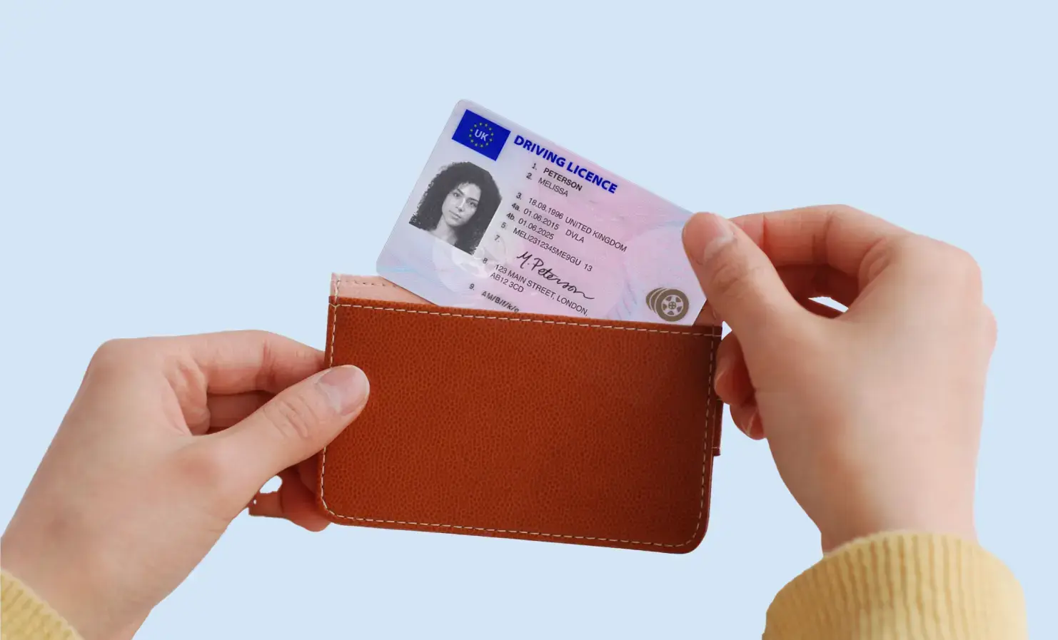 An image showing just person's hands. One hand is holding a card holder and the other is pulling a driving licence from it.
